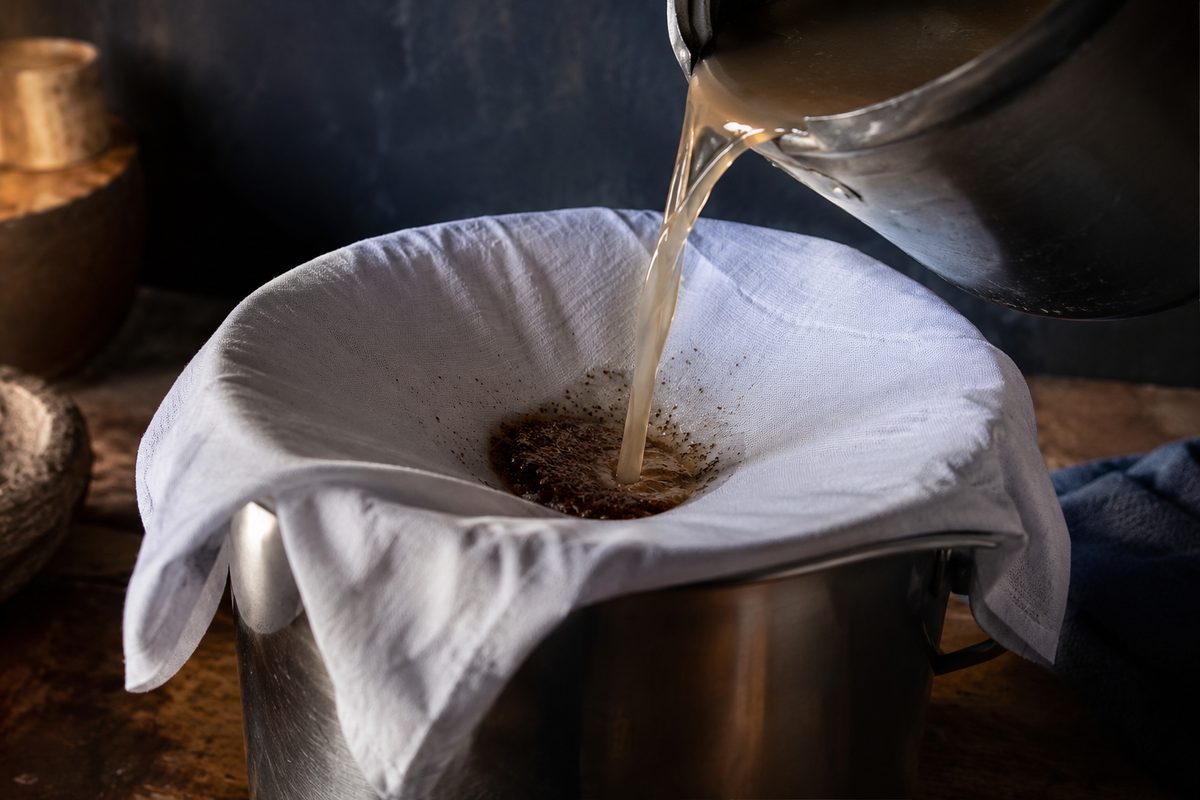 Troebel water door een schone doek gieten om vuil eruit te halen, als eerste stap voor het zuiveren